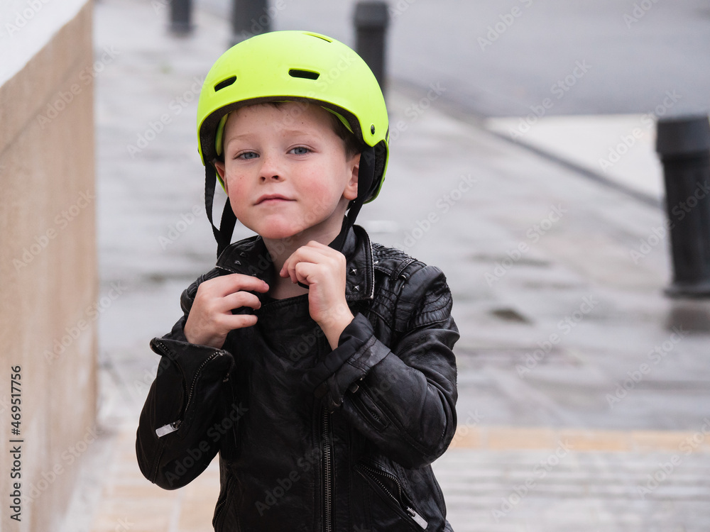 Smiling boy putting biking helmet in the park. Empty space for text
