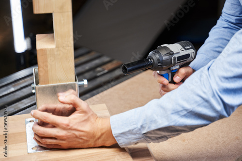 male hands tighten the nut on furniture with an automatic wrench
