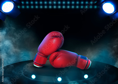 Pair of boxing gloves on black stand illuminated by spotlights