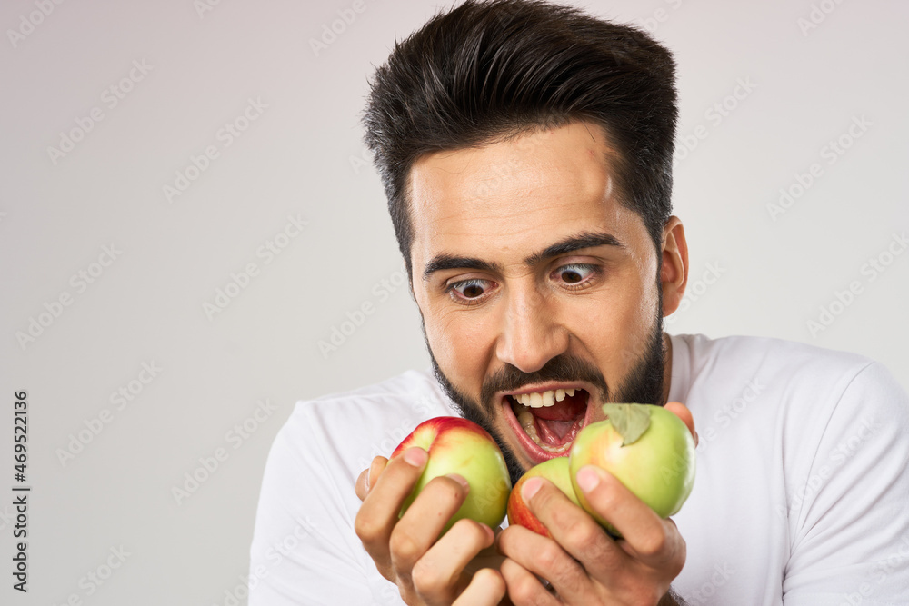 Cheerful man with apples in his hands in a white t-shirt fruits Cheerful man with apples in his hands in a white t-shirt fruits