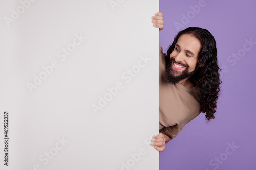Photo of cheerful man look hold paper placard advertise promotion isolated on purple color background