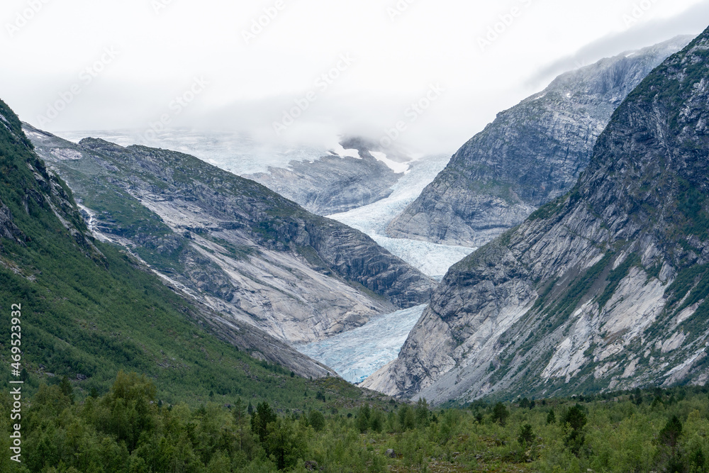 Glacier winding through a dramatic mountain valley in Norway, with mist rolling in. Glacier winding through a dramatic mountain valley in Norway, with mist rolling in.