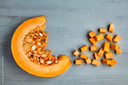 Fresh organic pumpkin slice and diced on a light blue wooden table photo