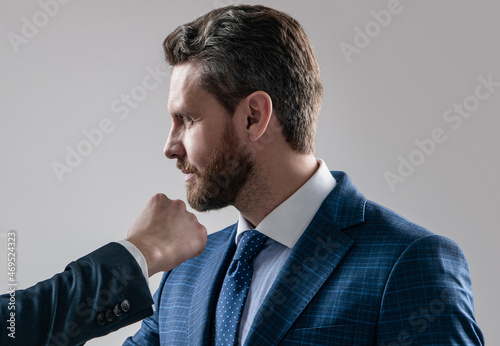Professional man manager taking male fist punch in face grey background, uppercut