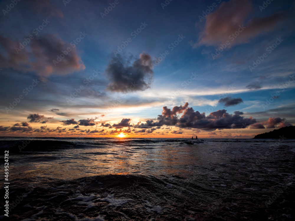 Fototapeta premium Beautiful sunset over the calm sea with cloud sky background. Sunset over tropical beach. Nature summer concept. Peak sunset over sea with yellow light reflect on sea water. Tranquil seascape.