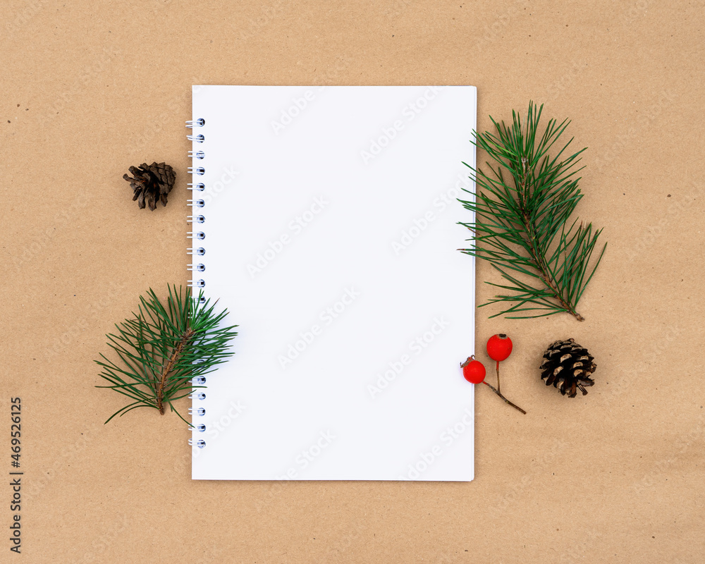 Evergreen sprigs of pine needles, notebook, cones and red berries with copy space.