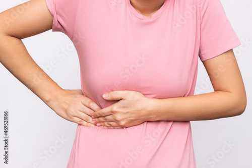 Wallpaper Mural Cropped shot of a young woman in a pink t-shirt holding her side with her hands isolated on a white background. Sore side under the rib after training. Stomach pain Torontodigital.ca
