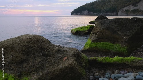 Beautiful Sea in autumn with epic sunset with green algae boulders. photo