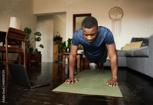 Young African man planking on an exercise mat at home