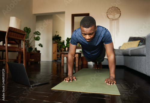 Fotografija Young African man planking on an exercise mat at home