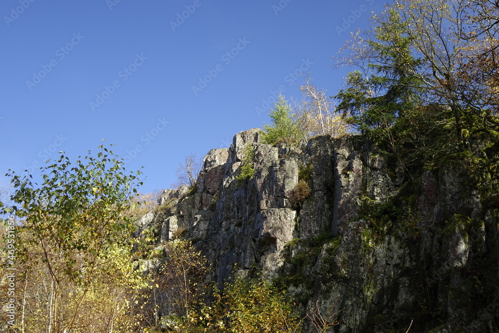 Mannfelsen rock formation (former quartzite stone quarrel pit for the Otzenhausen Celtic hill fort, ringwall, Hunnenring) with colourful autumn trees under a blue sunny sky, Otzenhausen, Nonnweiler, S