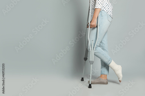 Fototapet Woman with injured leg using crutches on grey background, closeup