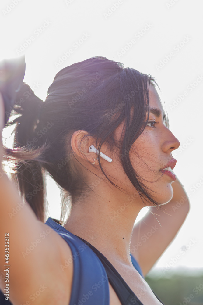 Woman in wireless earphones and activewear doing ponytail Woman in wireless earphones and activewear doing ponytail