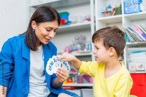A cute boy with a speech therapist is taught to pronounce the letters, words and sounds.