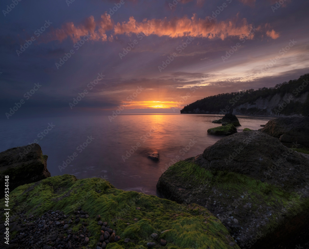 Beautiful Sea in autumn with epic sunset with green algae boulders.