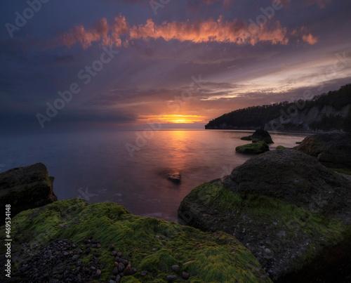 Beautiful Sea in autumn with epic sunset with green algae boulders.