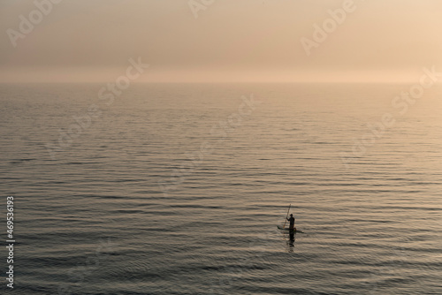 Silhouette of a man paddle boarding on the sea during sunset © Lucia Tieko