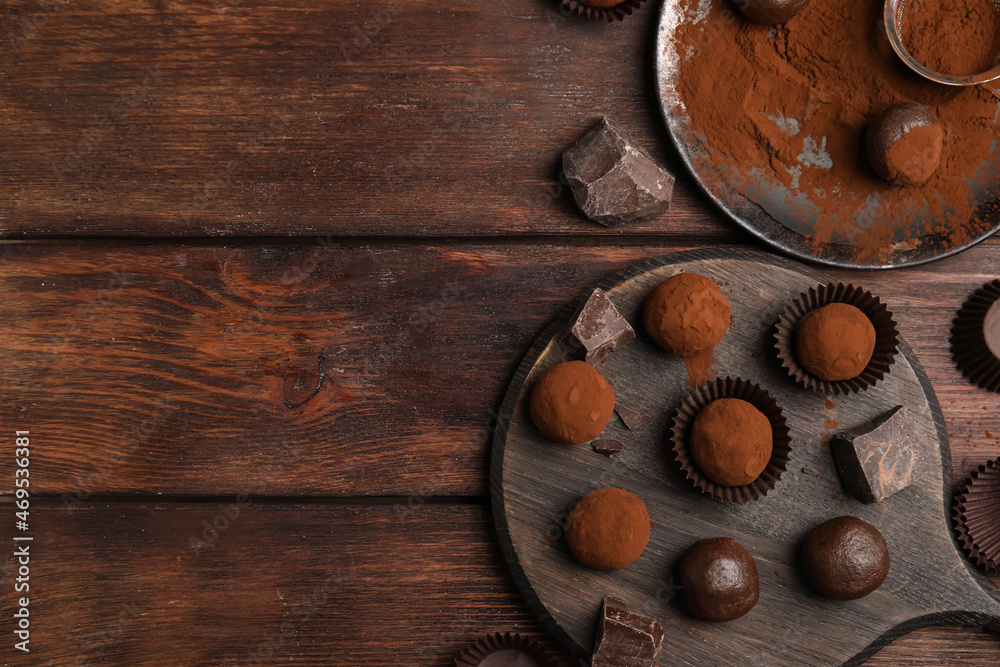 Delicious chocolate truffles powdered with cocoa on wooden table, flat lay. Space for text Delicious chocolate truffles powdered with cocoa on wooden table, flat lay. Space for text
