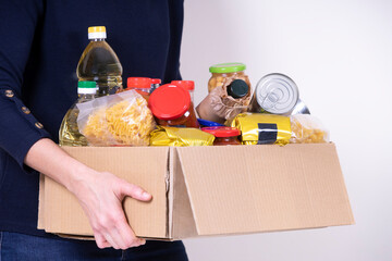 Woman volunteer hands holding food donations box with food grocery products