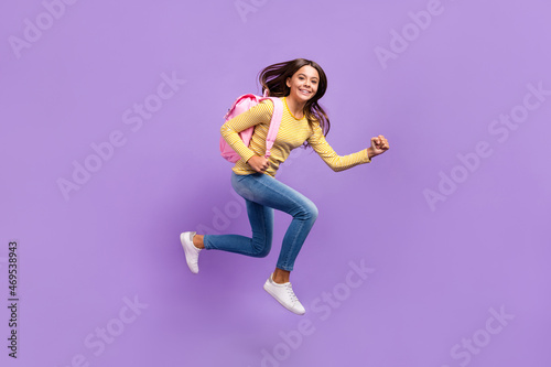 Full body profile side photo of youth lady scholar backpack jump run fast lesson isolated over purple color background