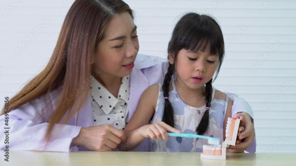 Asian female dentist teaching cute little girl brushing teeth with toothbrush and stomatologist telling girl child about oral hygiene in dental clinic, Education and prevention cavities concept. Asian female dentist teaching cute little girl brushing teeth with toothbrush and stomatologist telling girl child about oral hygiene in dental clinic, Education and prevention cavities concept.
