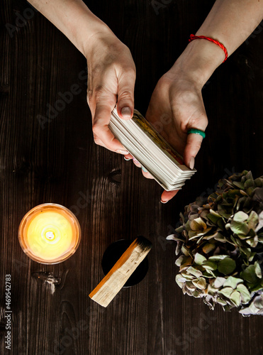 tarot cards in hands on a dark background in the light of a candle