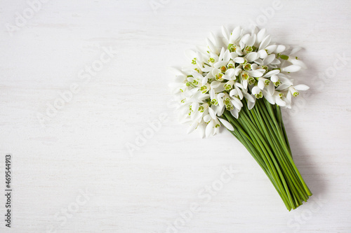 Bouquet of spring flowers of snowdrops on a white wooden background. postcard for congratulations, space for text.