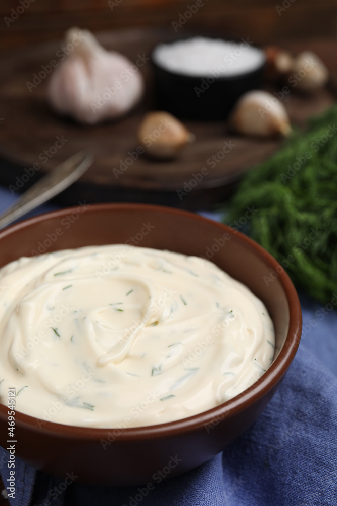 Tasty creamy dill sauce in bowl on blue kitchen towel, closeup Tasty creamy dill sauce in bowl on blue kitchen towel, closeup