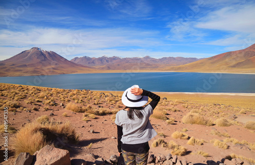 Female traveler being impressed with Miscanti lake, Amazing altiplanic lagoon in Los Flamencos national reserve, Antofagasta region, Chile photo