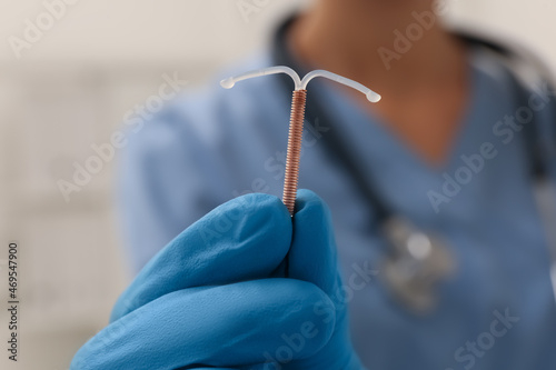 Cuadro en lienzo Doctor holding T-shaped intrauterine birth control device on blurred background,