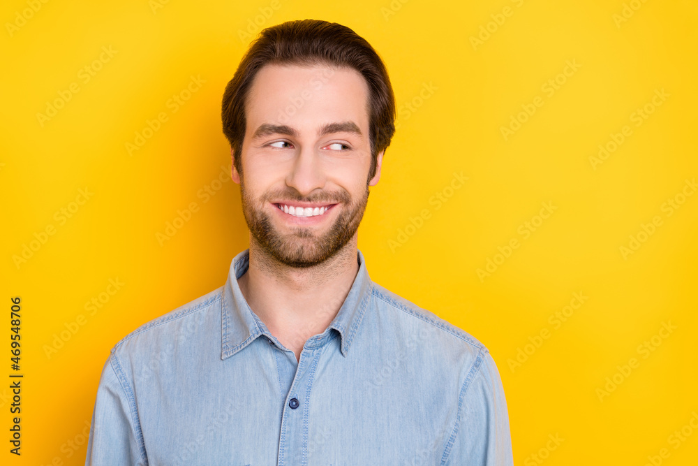 Photo portrait of young man smiling looking copyspace wearing jeans shirt isolated on bright yellow color background Photo portrait of young man smiling looking copyspace wearing jeans shirt isolated on bright yellow color background