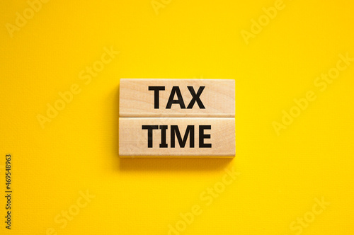 Tax time symbol. Concept words Tax time on wooden blocks on a beautiful yellow background. Business and tax time concept. Copy space.