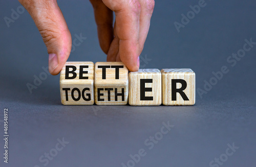 Better together symbol. Businessman turns cubes and changes the word together to better. Beautiful grey table, grey background, copy space. Business, motivational and better together concept. photo