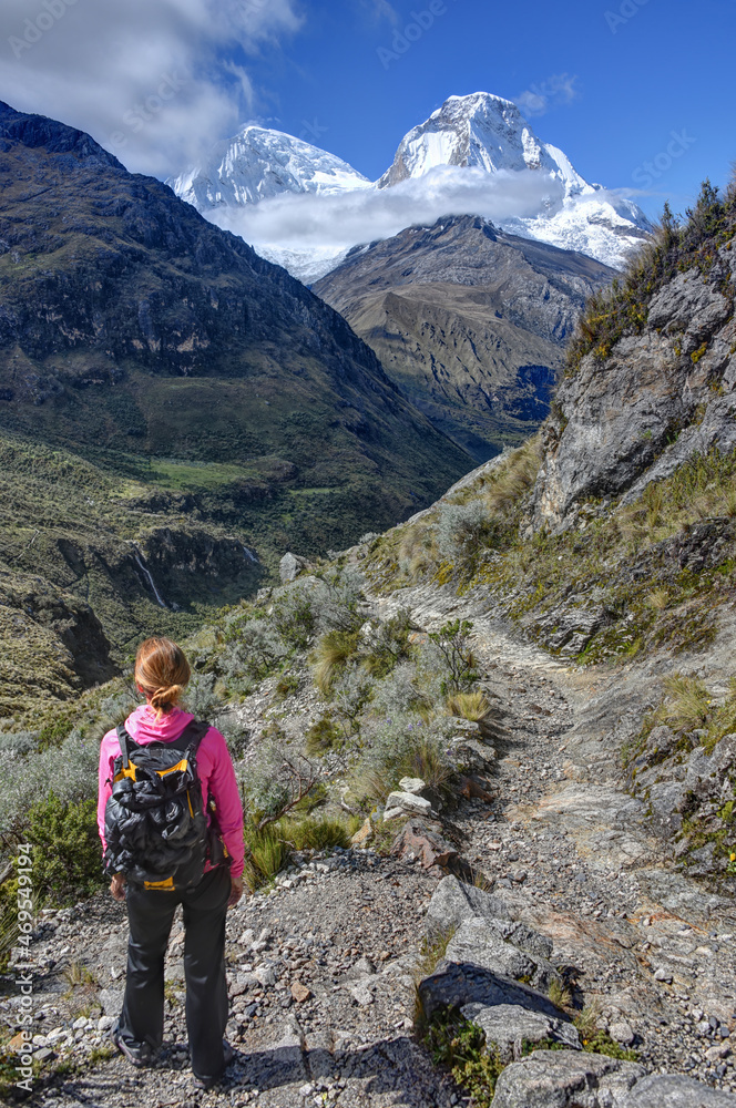 woman hiker on trail in the mountains with snow capped peak in background