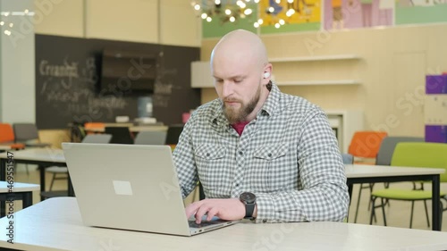 Young teacher who teaches online lessons sits in front of the computer and explains the topic to the students.
