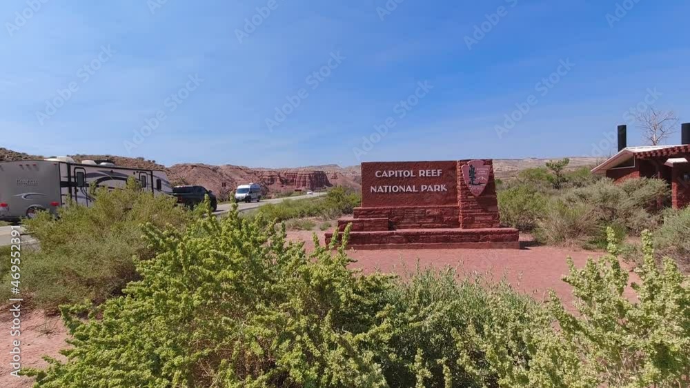 Entrance sign to Capitol Reef national Park along Utah State Route 24. Camera movement is a pedestal up from behind a green bush. Entrance sign to Capitol Reef national Park along Utah State Route 24. Camera movement is a pedestal up from behind a green bush.
