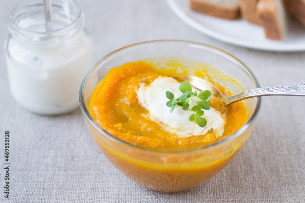 Pumpkin cream soup in a glass bowl and sour cream Pumpkin cream soup in a glass bowl and sour cream