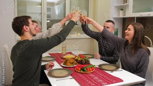 Big family celebration in Christmas day, two young couple have a meal smiling and felling happy in kitchen at home. drinking sparkling wine. Merry Xmas and happy new year.