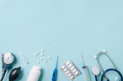 Medical concept, flat lay on blue background. Copy space. Stethoscope, tonometr, thermometer, pills and other medical equipment on blue, top view