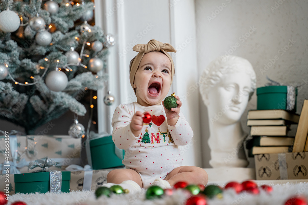 
little girl playing with Christmas decorations on the background of a Christmas tree