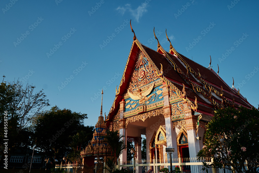 Naklejka premium Highly decorated red-golden roof of Wat temple depicting buddha and disciples.