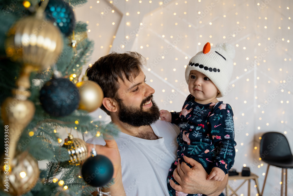 baby in a snowman hat decorates the Christmas tree with dad
baby in a snowman hat decorates the Christmas tree with dad