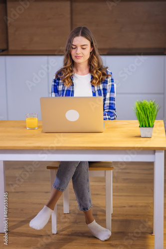 Image of smart positive woman 20s in casual clothing typing on l