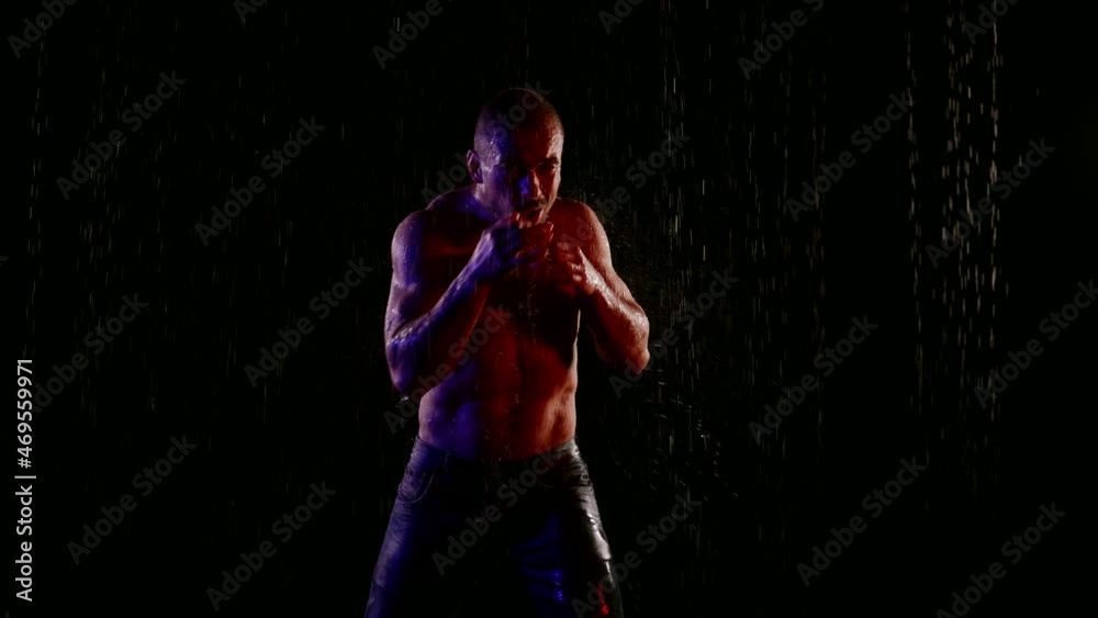 trained fighter is waving fists in rain in nighttime, training alone trained fighter is waving fists in rain in nighttime, training alone