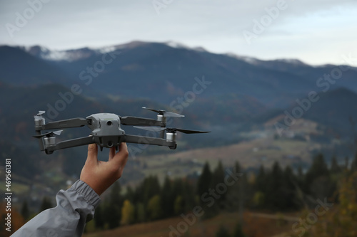 Man with modern drone in mountains, closeup. Space for text