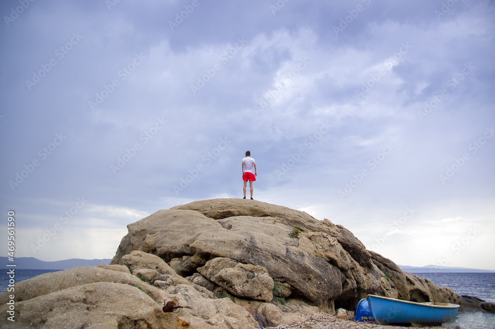 Sylwetka młody mężczyzna stojący na skale na tle pięknego nieba - obrazy, fototapety, plakaty 