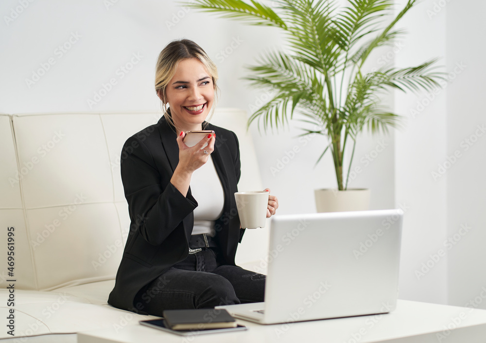 young woman talking on her smartphone while having coffee before starting work young woman talking on her smartphone while having coffee before starting work