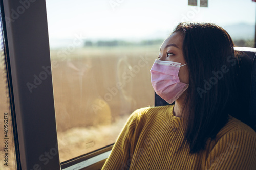 Obraz na płótnie Close up of young Asian pretty woman travelling in bus with pink mask looking through the window w salonie