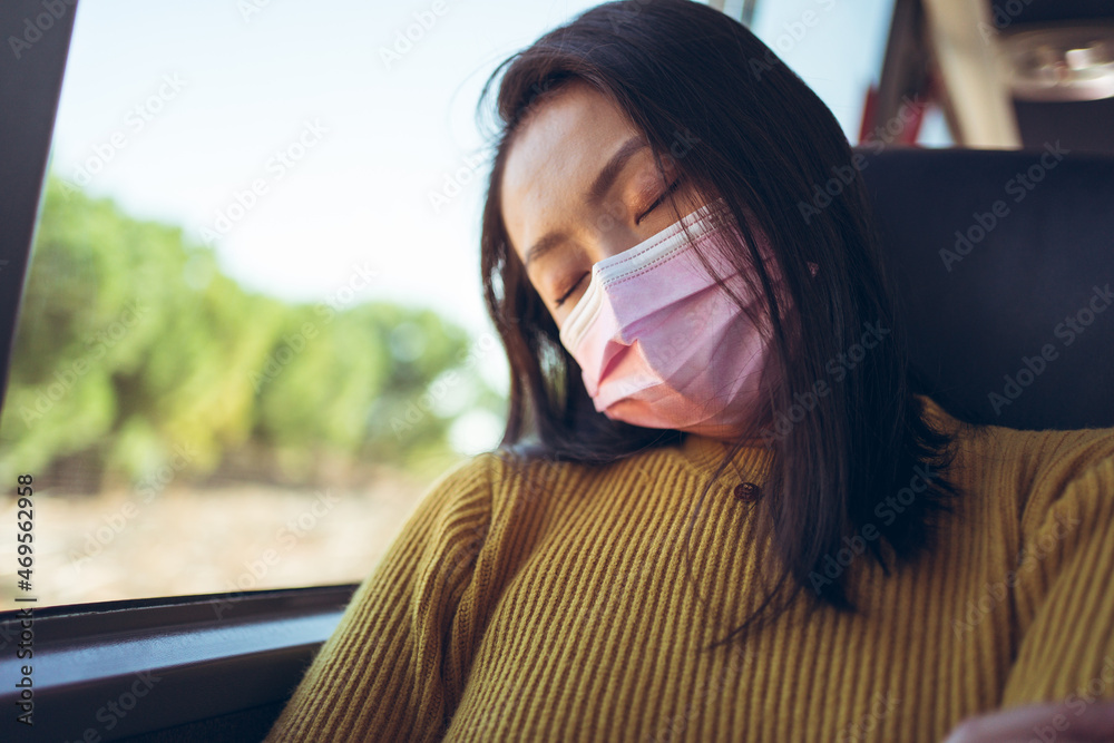 Young Asian pretty woman sleeping while travelling in empty bus with pink mask