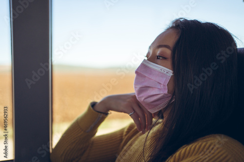 Obraz na płótnie Young Asian pretty woman travelling in empty bus with pink mask looking through the window w salonie